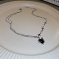 Detail of silver heart pendant with black gemstone and sparkling rhinestones on white plate - Black Heart