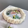 Detailed close-up of a pleated cream satin headband with elegant scrunchie texture - Milky White