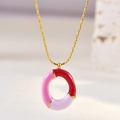 Close-up of pink and purple enamel round pendant on a gold chain necklace - Letter O