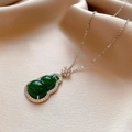 Silver necklace with green gourd pendant and diamonds on beige silk background - Green Gourd Rhinestone Style