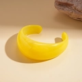 Detailed view of a thick yellow resin open cuff bracelet on a minimalist stone background - Yellow