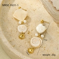 Detailed view of bohemian gold ocean earrings with seashells and pearls on sand texture - White Shell Earrings