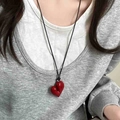 Detail view of a vintage hollow heart-shaped red resin pendant on a black leather cord - 22# Necklace-Red