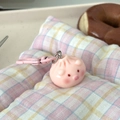 Close-up of pink pig bun keychain pendant on a blue checkered fabric background - Pink Pig