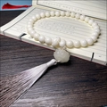 Chinese white bodhi seed bracelet with lotus charm and long silk tassel on vintage book - Hand-held White Jade Bodhi (Luminous Lotus)