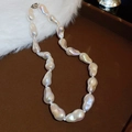 Detail of white baroque pearl necklace with iridescent luster on a dark tray - White (Medium Size)