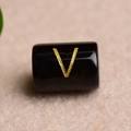 Macro shot of a black rectangular bead featuring a gold-stamped letter V for DIY jewelry - Letter V