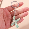 Detail of letter K keychain with green iridescent glitter in transparent resin - Letter K