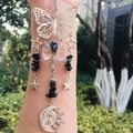 Macro detail of silver butterfly suncatcher with black stones and crystal hanging pendants - Snowflake Obsidian