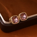 Macro shot of square-cut pink crystal earrings with gold base on brown leather - Light Purple