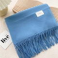 Flat lay of soft blue tassel scarf with fine cashmere-like texture on textured background - Blue