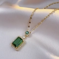 Detalle del colgante de circonita verde esmeralda con cadena dorada sobre tela de seda - Collar de Esmeralda