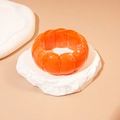 Macro shot of orange geometric acrylic bead bracelet on a textured stone base - Orange
