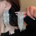 Gros plan d'un mannequin portant des boucles d'oreilles argentées à pompon et cœur - 42# Pampille en Cœur Rose Tige Argent (HE3995)