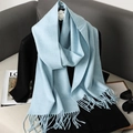 Soft light blue faux cashmere scarf with fringe displayed on a black outfit mannequin - Denim Blue