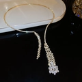 Macro shot of gold tassel pendant necklace with shimmering white rhinestones detail - Gold Rhinestone Clavicle Chain