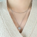 Double layered silver heart necklace with star engraving worn on beige knit sweater - Silver