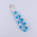 Detailed close-up of handmade woven blue and white daisy flower keychain with gold clasp - Blue