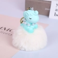 Detail von blauem Plüsch-Einhorn mit Perlenkette an weißem Kunstfell-Bommel-Anhänger - Weiß