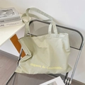 Dettaglio della borsa tote in tela verde chiaro con testo Magasin de Croissants sulla sedia - Grigio chiaro