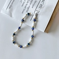 Blue Evil Eye beaded phone lanyard with white clay spacers and gold beads on white paper - White