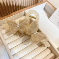 Détail de la pince à cheveux papillon avec broderies dorées et accents de perles - Champagne