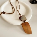 Détail du pendentif géométrique en résine à motif écaille sur cordon marron sur plat blanc - Collier-Brun-Jaune