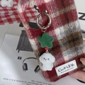 Macro shot of a red check phone case with a plush dog and green star keychain accessory - Green Star - Puppy