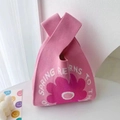Pink knitted tote bag featuring a magenta flower pattern and Spring Returns text - Pink Sunflower