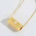 Macro shot of gold Lucky pillar pendant with heart motif and zircon inlay detail - White