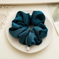 Detail of teal premium satin scrunchie with a silver metal tag on a ceramic plate - Indigo Blue