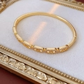 Vista macro dettagliata di un bracciale dorato con motivi traforati e intarsio di zirconi - Oro