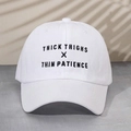 Close-up of black THICK THIGHS X THIN PATIENCE embroidery on a white twill cotton baseball cap - One Size / White