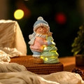 Dettaglio di un ragazzo natalizio in ceramica con un albero luminoso a LED caldi - Stile Ragazzo Dipinto
