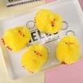 Detail shot of four yellow plush chick keychains with silver metal rings on a white tray - Yellow Duck