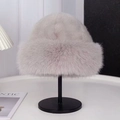 Close-up of a light grey plush winter hat displayed on a sleek black metal stand - Beige