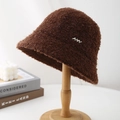Detailed texture of brown curly teddy fleece bucket hat with silver NW metal emblem - Coffee