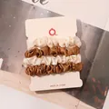 Detail of 4-piece satin scrunchies set in beige and bronze on a white display card - Off-White and Gold