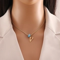 Close-up of golden necklace with evil eye and letter V charms worn by a model - Letter V (N1339)