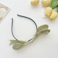 Detail of light green satin bow headband featuring elegant layered silk fabric texture - Light Green