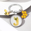 Close-up of silver keychain with bee charms and letter J glass dome pendant detail - Letter J
