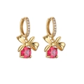 Detailed close-up of gold bow earrings with square-cut red zircon stones on white background - Earrings / Gold Rose Red Zirconia