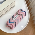 Macro detail of pink knitted makeup bag with colorful wave patterns and a fabric label - Pink & Blue Wave Pattern