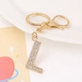 Macro detail of golden metal letter L keychain pendant with sparkling white rhinestones - Letter L