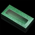Detail of green glitter eyelash box with transparent window on reflective black surface - Dark Green