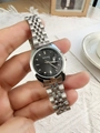 Close-up of a silver steel women's watch featuring a black dial and date window display - Black