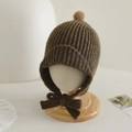 Detail of baby knit hat with pompom and ear flaps on a wooden model stand - 2-5 Years Old / Brown