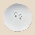 Detailed top view of C-shaped silver earrings with pink gemstones on a ceramic plate - Pink Round Pendant (23071923)