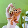 Brown dinosaur mini game keychain with gold ring and bell accessory for backpacks - Brown