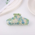 Dettaglio di un grande fermaglio per capelli in acetato con trama marmorizzata verde e blu - Smeraldo